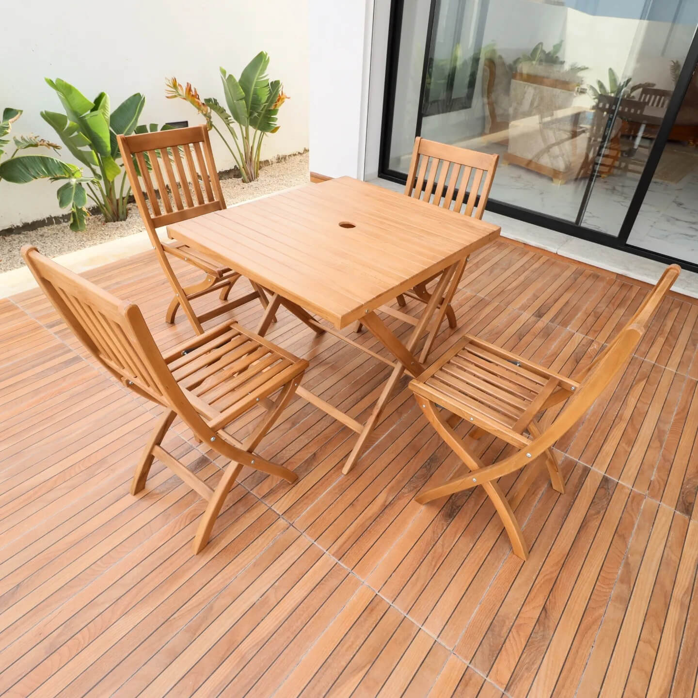 Ensemble de salle à manger de jardin en bois massif avec une table pliable et 4 chaises pliantes assorties sur une terrasse.