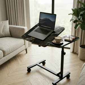 Table de lit roulante effet marbre noir dans un salon moderne, avec ordinateur portable sur plateau incliné et café sur plateau fixe.